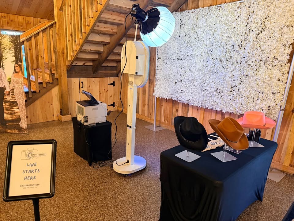 PoseWithUs photo booth setup with white floral wall backdrop and prop table at a GTA venue